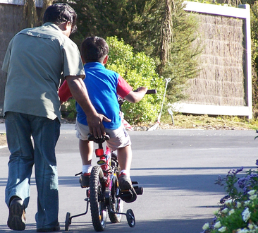 parent helping child learn to ride a bike